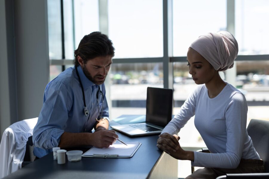 Male doctor discussing information with a female patient at an office desk