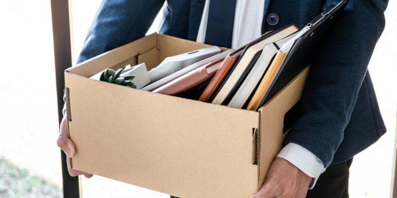 Man holding box filled with belongings from work desk