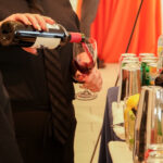 Close up of a bartender pouring red wine into a wine glass