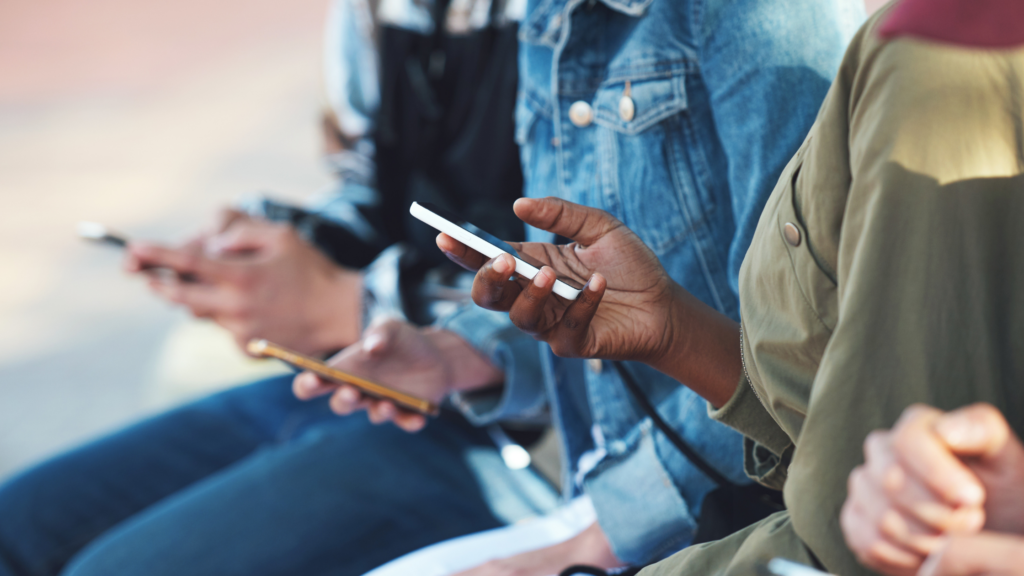 Close up on three people's hands. Each person has a smart phone in their hand.