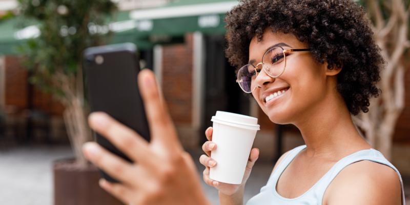 A woman takes a selfie while holding a cup of coffee