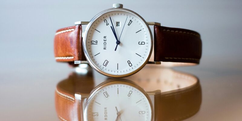 men's watch with a brown leather strap on a table