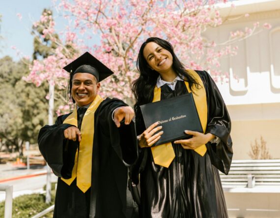 man and woman in graduation black robes smiling holding black diploma case